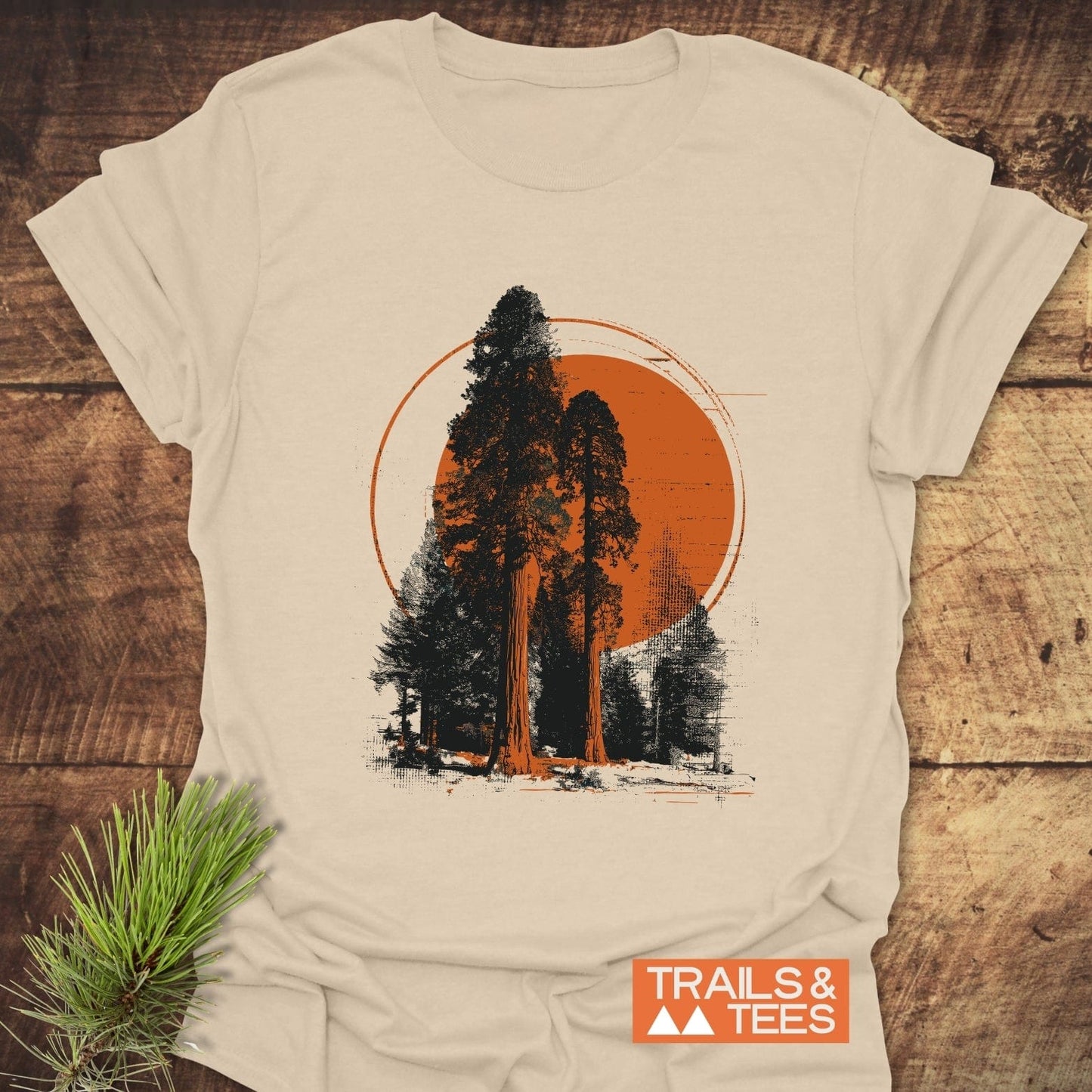 Sequoia T-Shirt featuring two conifer trees silhouetted against an orange circle, highlighting outdoor adventure. Crafted from soft cotton for comfort and durability.