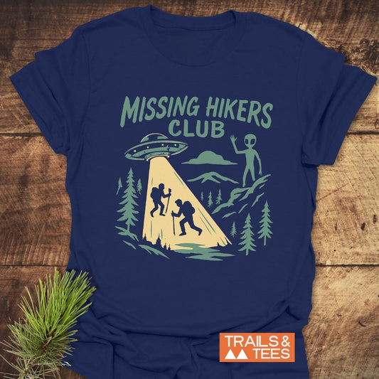 Missing Hikers Club T-Shirt features a UFO scene with hikers and an alien. Made from soft, durable cotton, it offers comfort and adventure appeal.