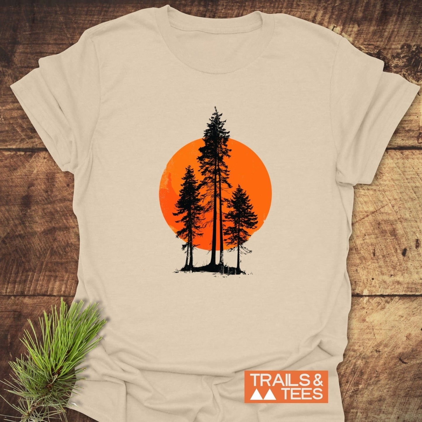 Sunset Trees T-Shirt featuring black evergreen silhouettes on an orange sun, laid flat. Made from soft ring-spun cotton with durable prints.