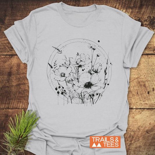 Wildflower Circle T-Shirt featuring a black line-art illustration of wildflowers on soft, lightweight cotton, laid flat with TRAILS & TEES logo visible.