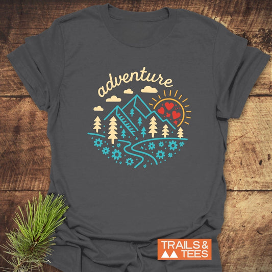Adventure Whimsical T-Shirt with colorful mountain and sun graphic, laid flat. Made from soft cotton for comfort, ideal for outdoor enthusiasts.