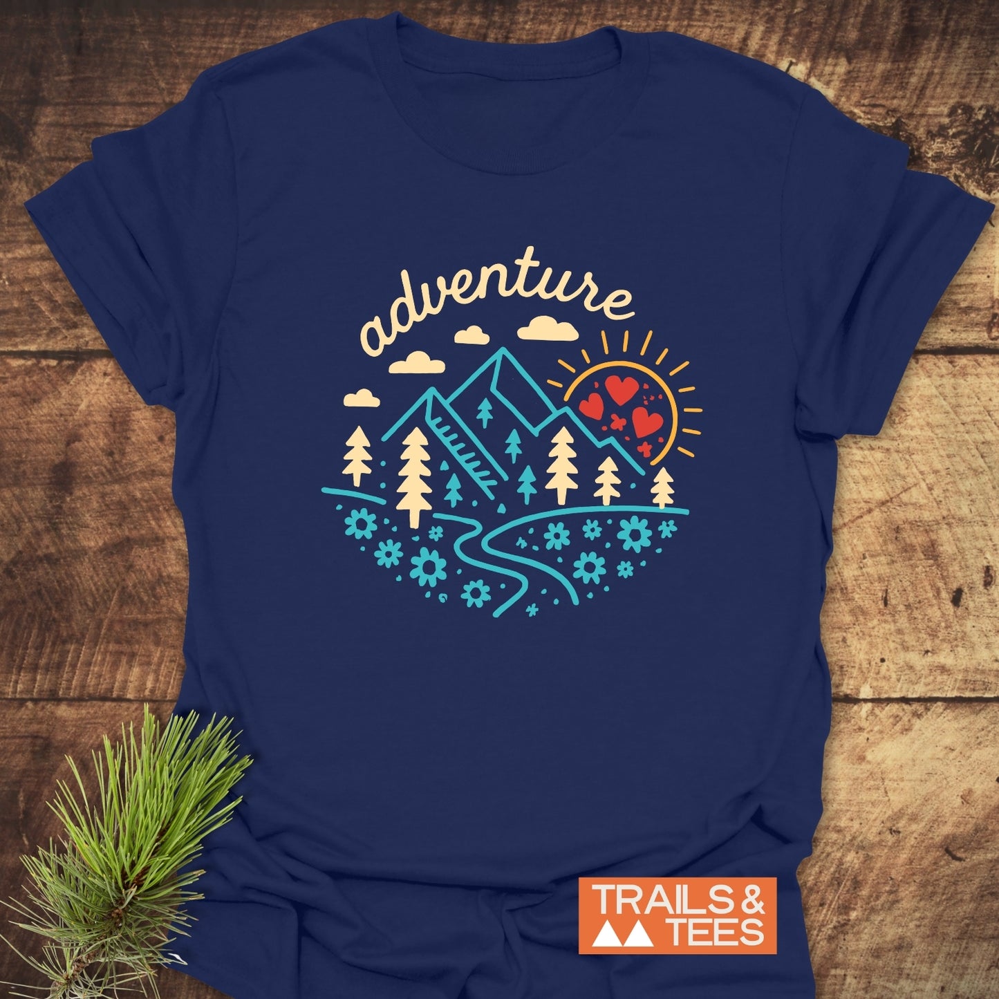 Adventure Whimsical T-Shirt featuring a geometric mountain scene with a sun, trees, and river; crafted from soft cotton for everyday outdoor adventures.