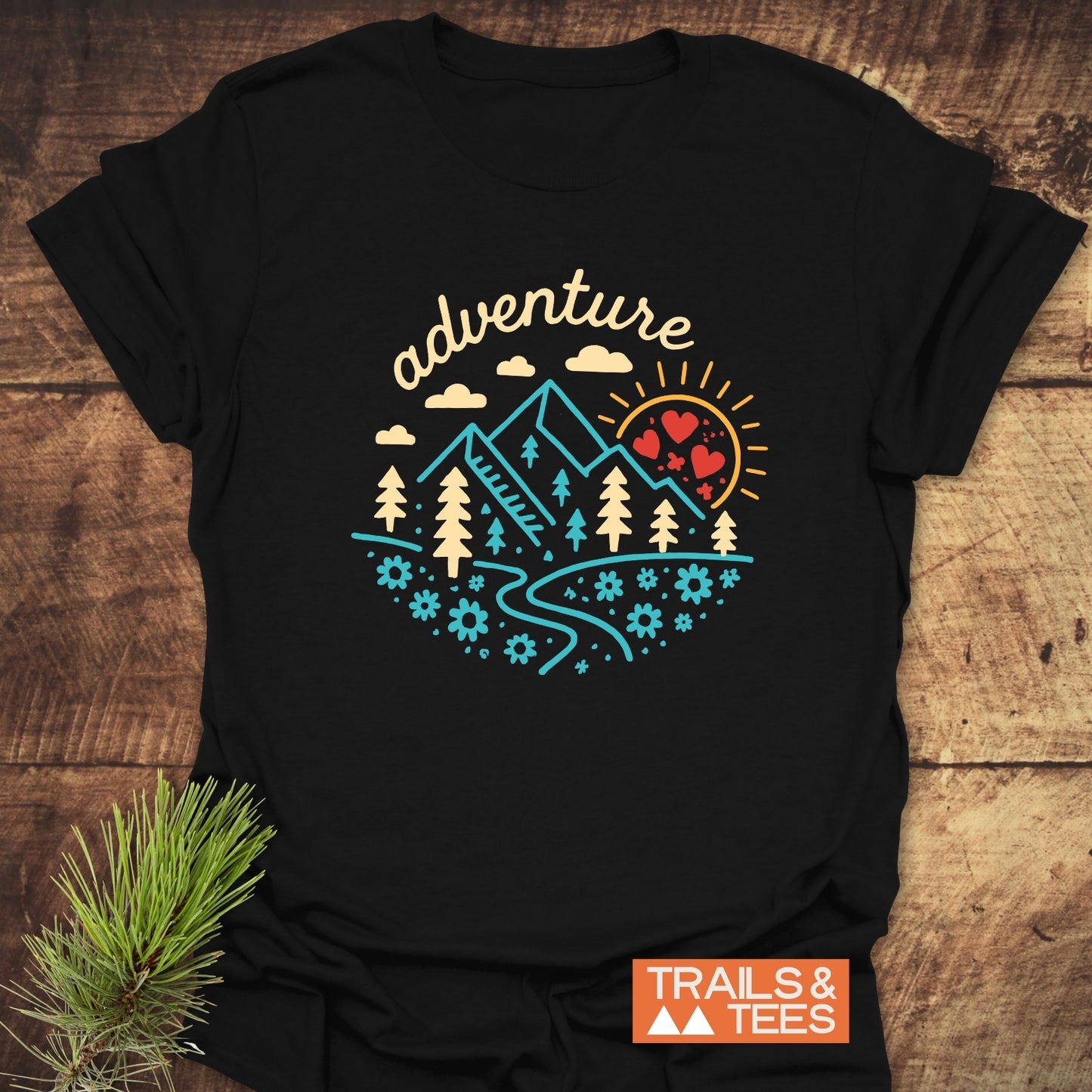 Adventure Whimsical T-Shirt featuring a colorful landscape design with mountains, trees, and sun. Made from soft cotton, perfect for everyday outdoor enthusiasts.