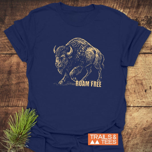 Roaming Bison T-Shirt, navy-blue with a distressed gold bison print and ROAM FREE slogan, laid on wood. Features durable, soft ring-spun cotton.