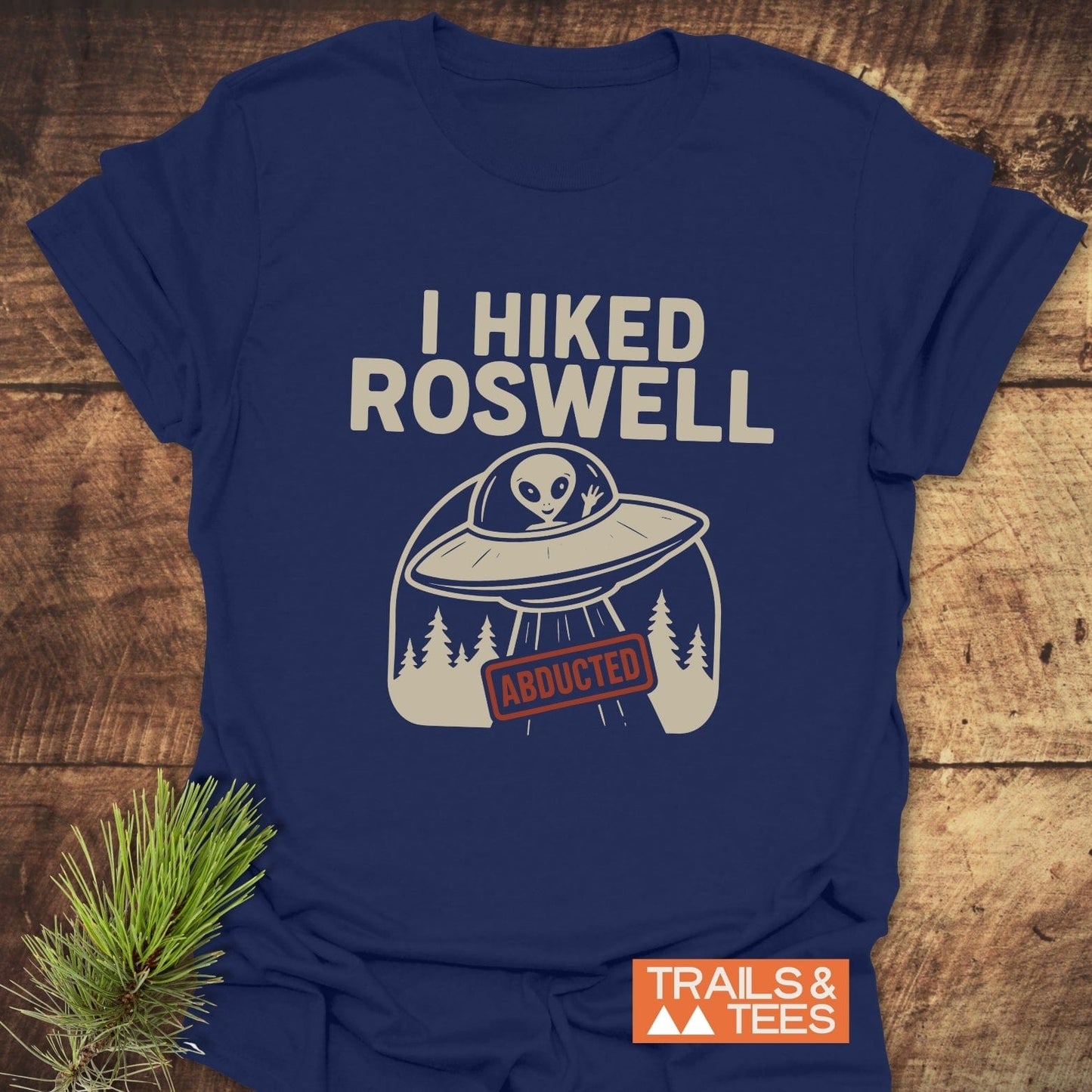 Navy-blue I Hiked Roswell T-shirt featuring a UFO graphic and waving alien, highlighting durable, comfortable design by Trails & Tees for outdoor enthusiasts.