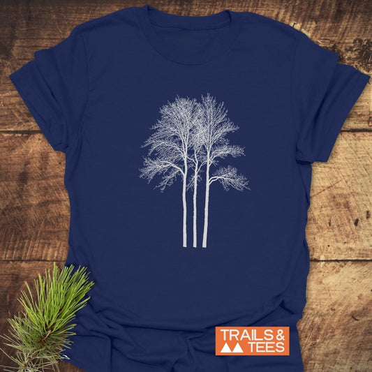 Tree Silhouettes T-Shirt with white tree design on dark-blue fabric, featuring a TRAILS & TEES logo and pine sprig for styling, emphasizing outdoor adventures.