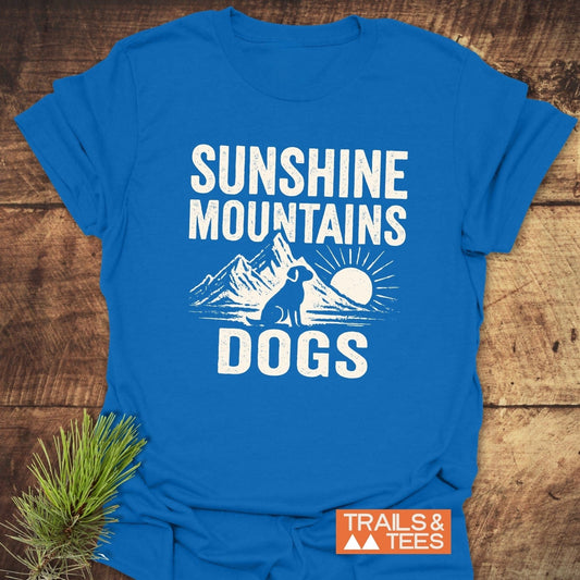 Sunshine Mountains Dogs T-Shirt featuring a mountain, sun, and dog silhouette. Lightweight, ring-spun cotton with durable prints and a TRAILS & TEES logo.