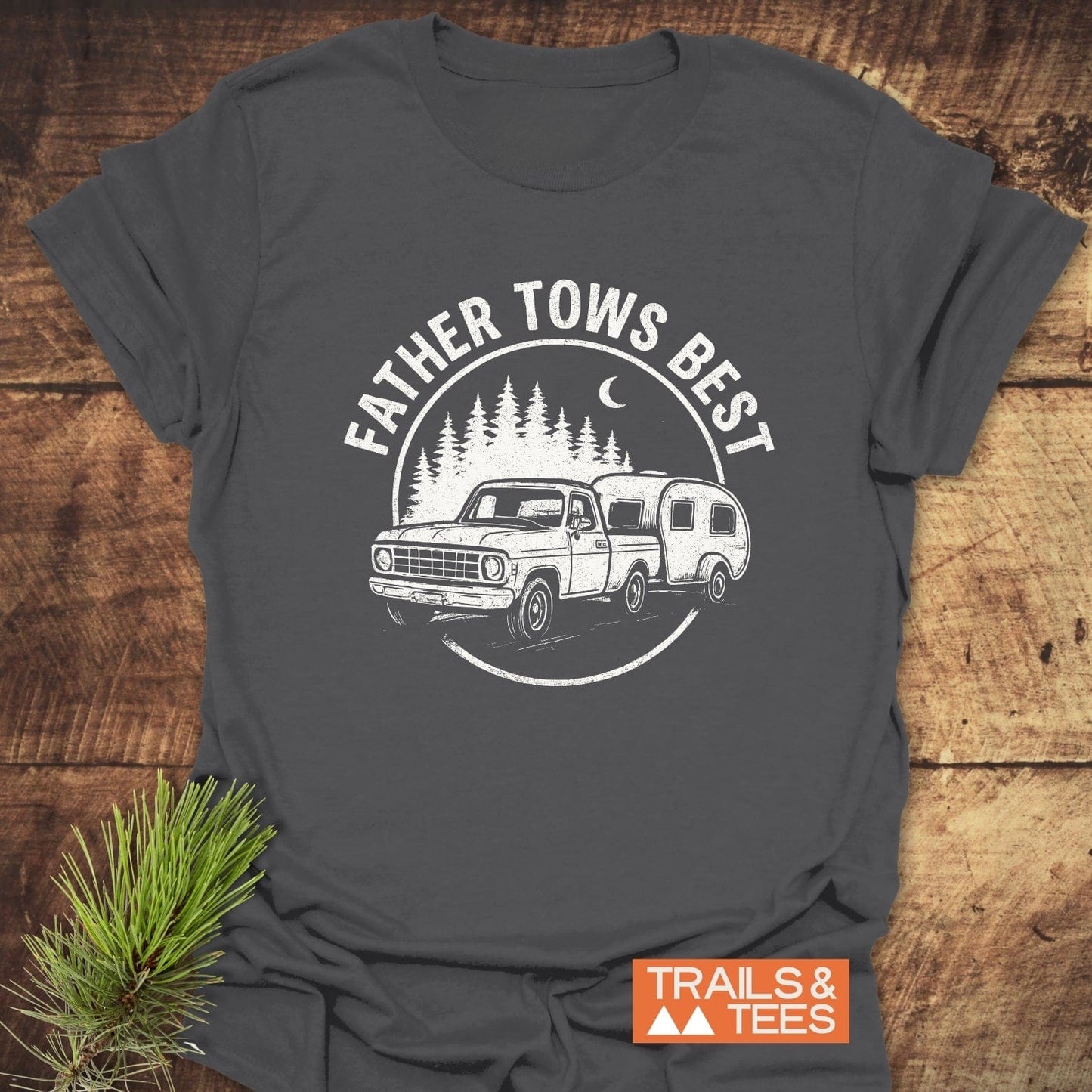Father Tows Best T-Shirt: Dark-gray tee with vintage truck and camper graphic, pine trees, crescent moon, and slogan. Soft, pre-shrunk cotton for outdoor enthusiasts.
