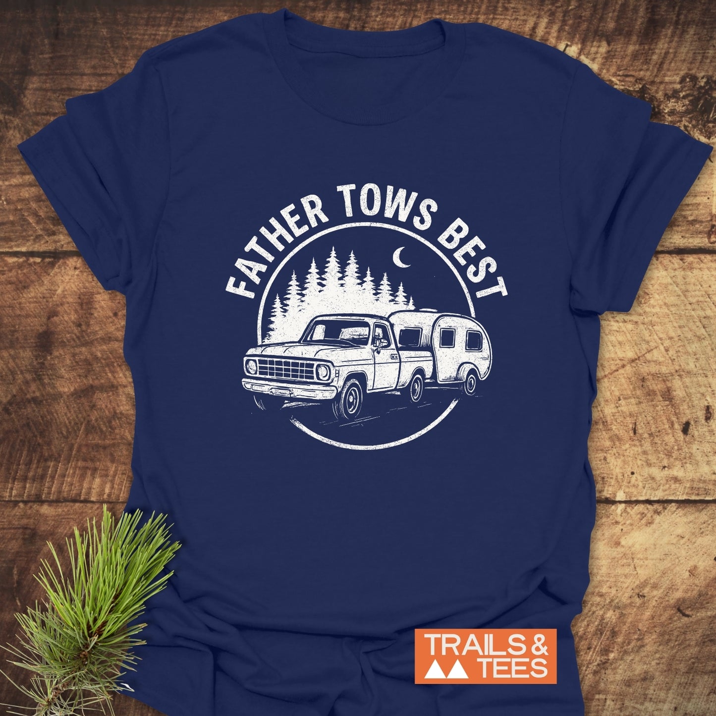 Father Tows Best T-Shirt featuring a pickup truck and camper print, styled with a pine sprig, embodies outdoor adventure in soft, durable cotton.