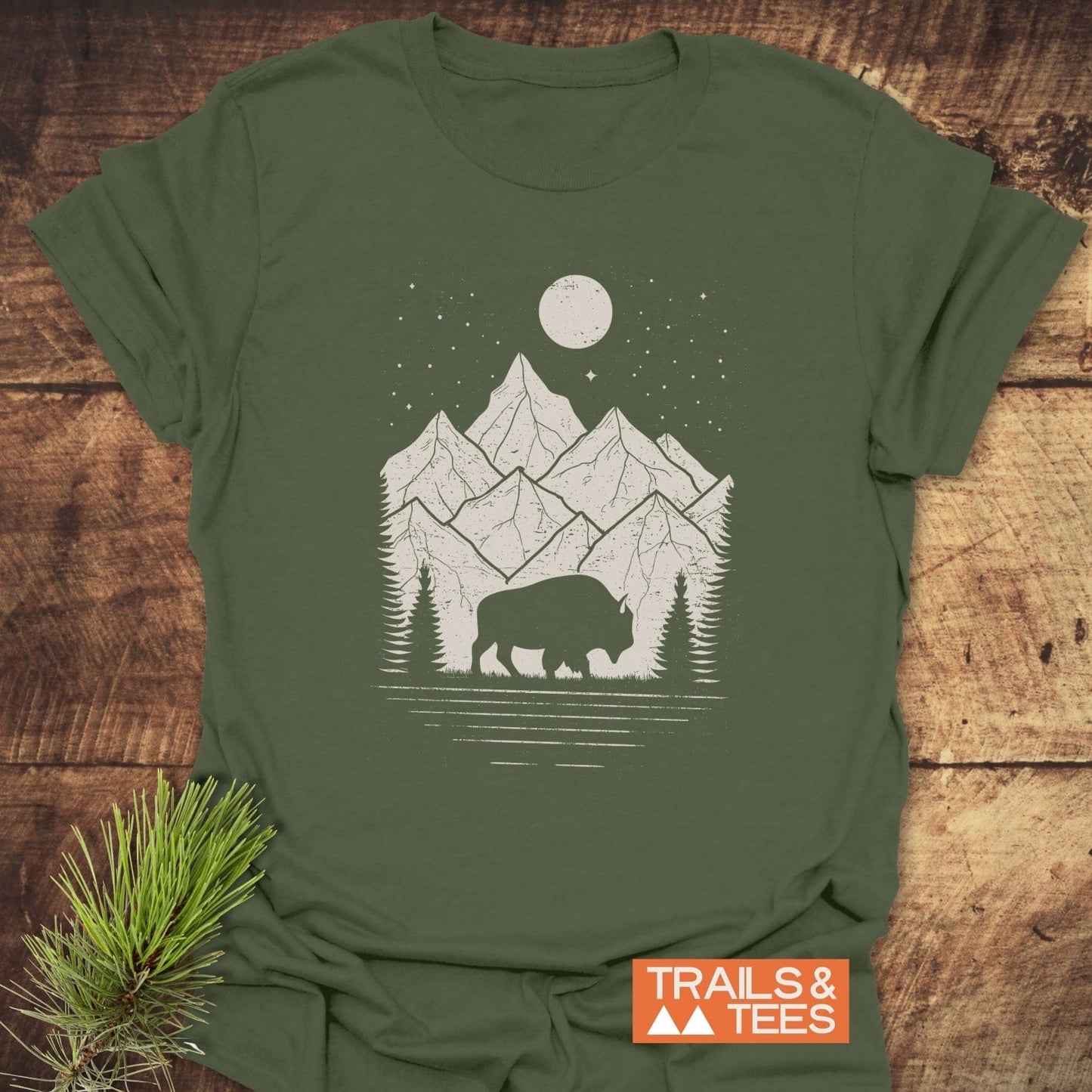 Nightsky Buffalo T-Shirt featuring a bison silhouette, pine trees, and mountains under a starry sky, crafted from soft ring-spun cotton for everyday adventure.