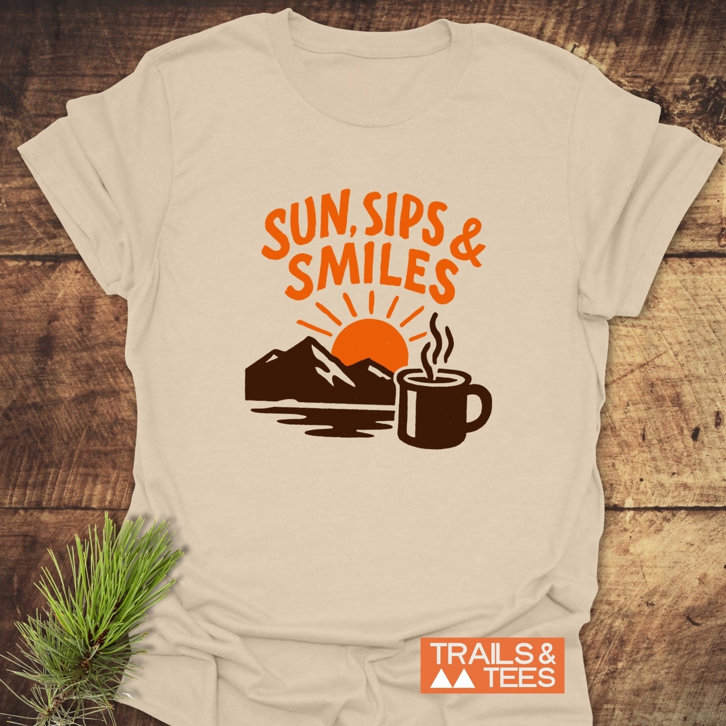 Sun, Sips, Smiles T-Shirt with mountain and sun graphic, crafted from soft cotton for comfort and adventure, featuring durable prints and taped shoulders.