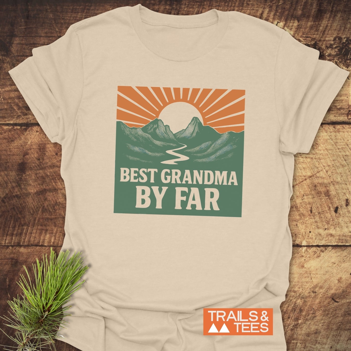 Best Grandma By Far T-Shirt featuring a retro sun, mountains, and river graphic, emphasizing outdoor adventure, crafted from soft ring-spun cotton by Trails & Tees.