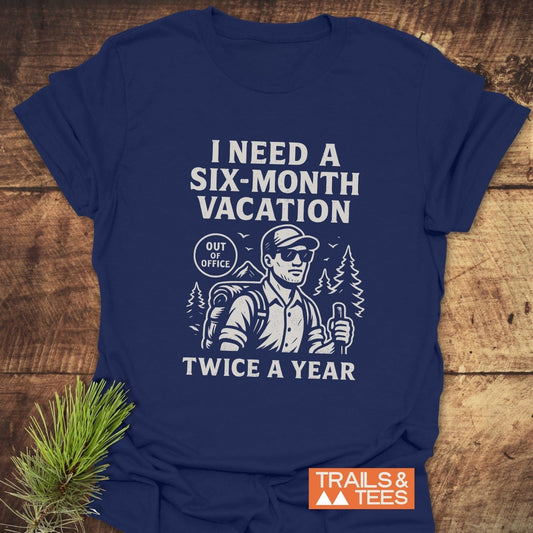 Navy-blue Six-Month Vacation T-Shirt featuring a hiker design with a slogan, emphasizing outdoor adventure. Includes TRAILS & TEES logo, crafted for comfort and durability.
