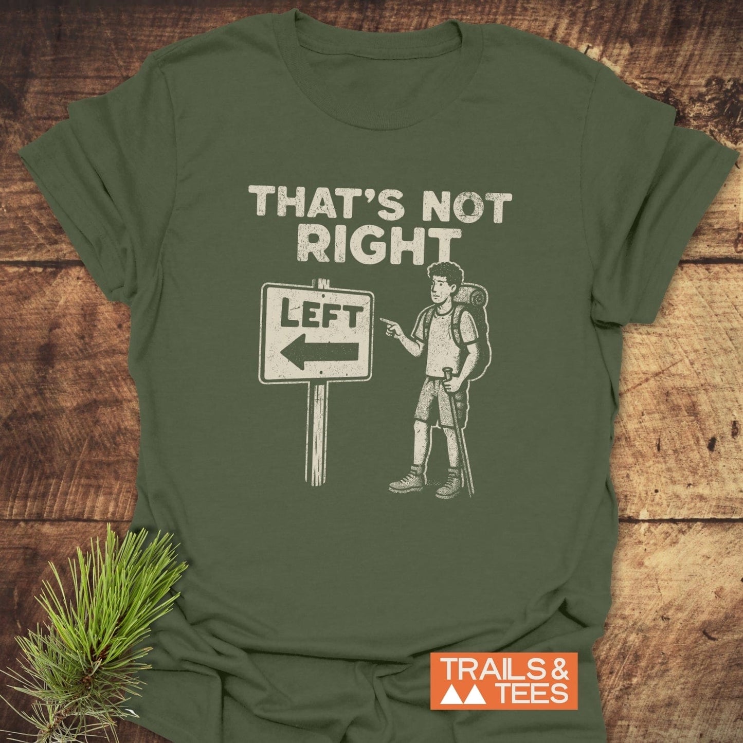 Olive-green That's Not Right Funny T-Shirt with white chalk-style text and graphic, featuring a puzzled hiker by a LEFT sign; branded by Trails & Tees.