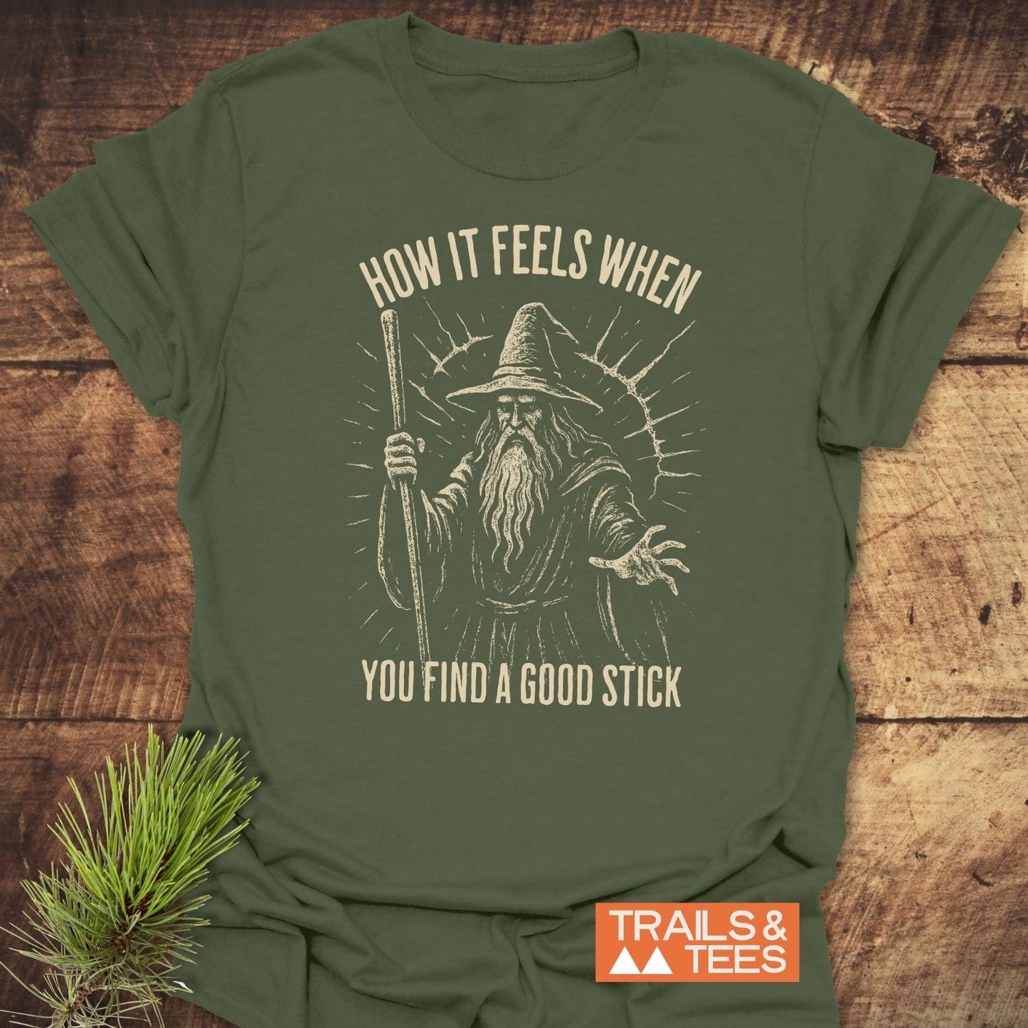 Good Stick T-Shirt showing a vintage wizard design, surrounded by text, on soft cotton. Includes Trails & Tees logo, ideal for outdoor enthusiasts.