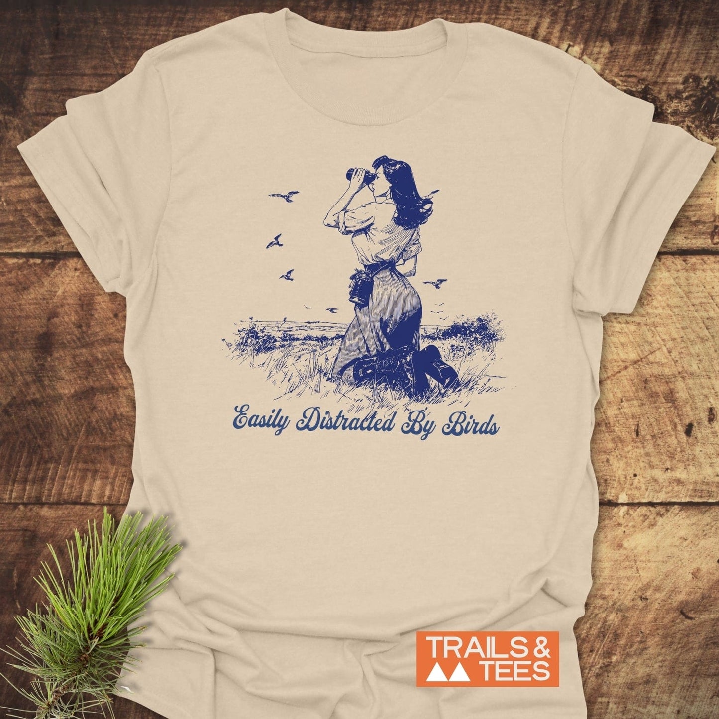 Easily Distracted By Birds T-Shirt featuring a blue illustration of a woman with binoculars, crafted from soft ring-spun cotton for outdoor enthusiasts.