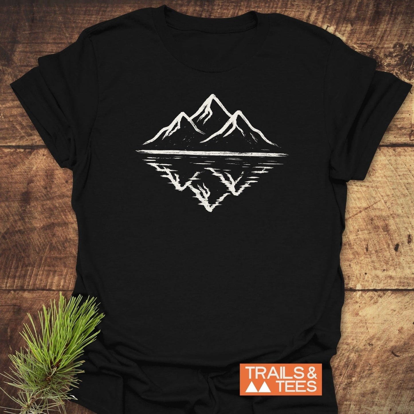 Mountain Reflection T-Shirt featuring a hand-drawn mountain and lake graphic, crafted from soft cotton for comfort and durability, ideal for outdoor enthusiasts.