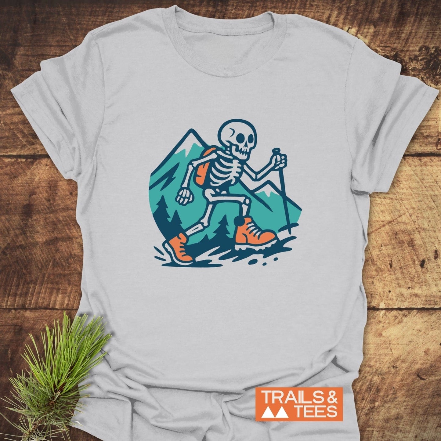 Long Way To The Top – Skeleton Hiking T-Shirt featuring a cartoon skeleton with hiking gear, mountain, and tree design, perfect for outdoor enthusiasts.