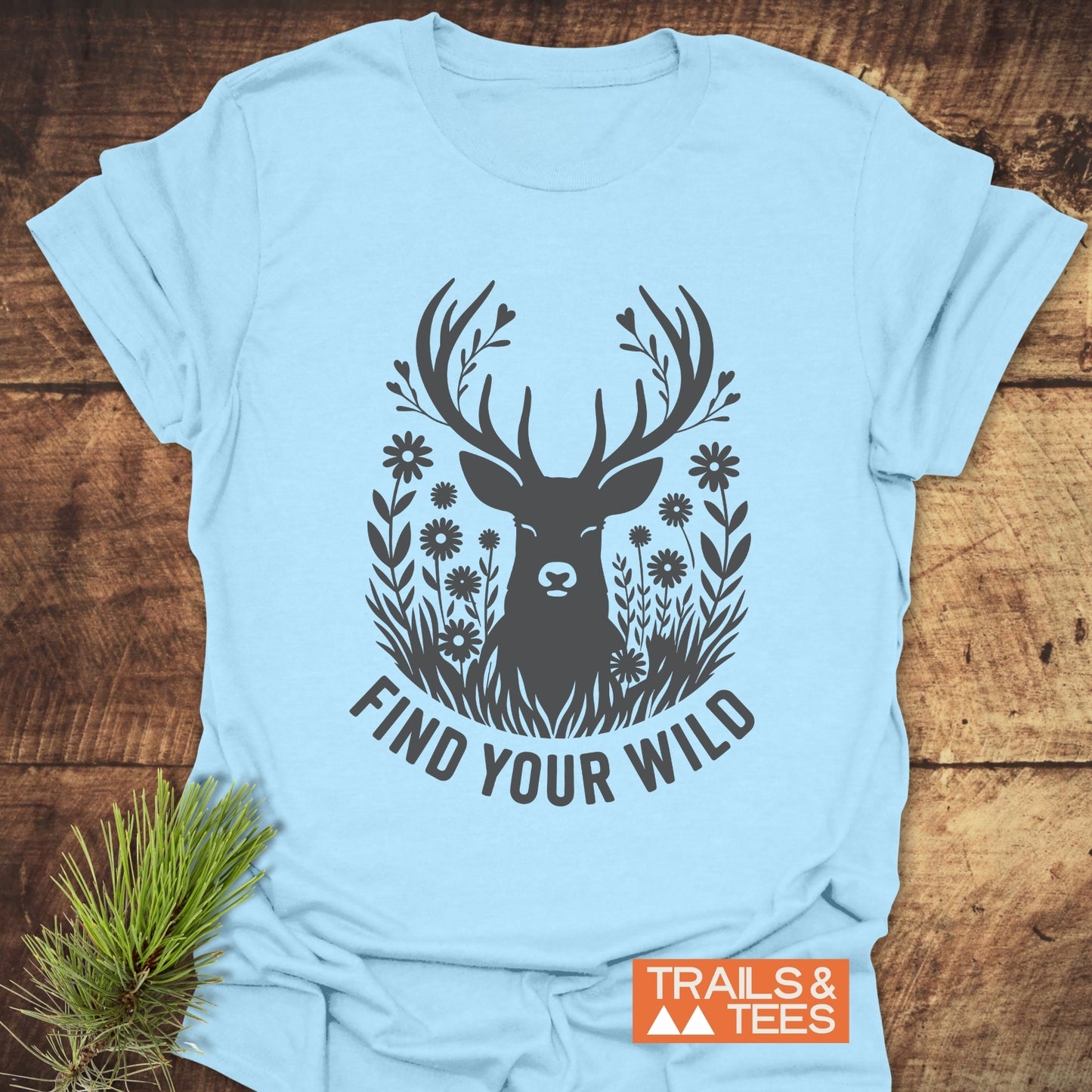 Find Your Wild T-Shirt with a stag silhouette and slogan, laid on wood. Made from soft, lightweight cotton, ideal for outdoor adventures.