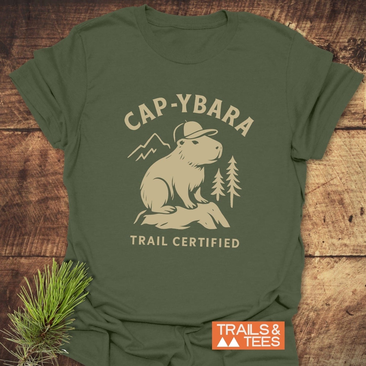 Cap-ybara T-Shirt featuring a capybara graphic with CAP-YBARA and TRAIL CERTIFIED text, highlighting outdoor adventure spirit. Includes Trails & Tees logo.