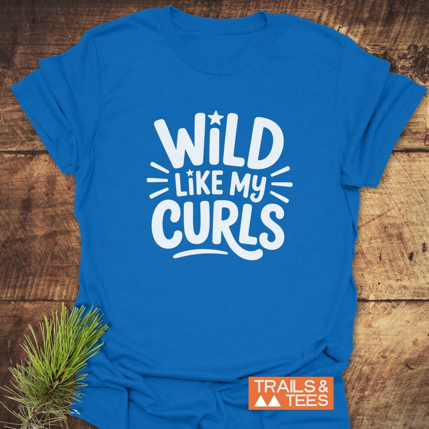 Wild Like My Curls T-Shirt with bold white print, laid flat, showcasing a Trails & Tees logo, designed for comfort and adventure.