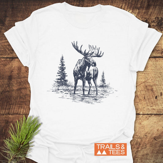 Moose T-Shirt with a detailed sketch of a bull moose in water, crafted from soft cotton for comfort, laid flat with a pine branch beside it.