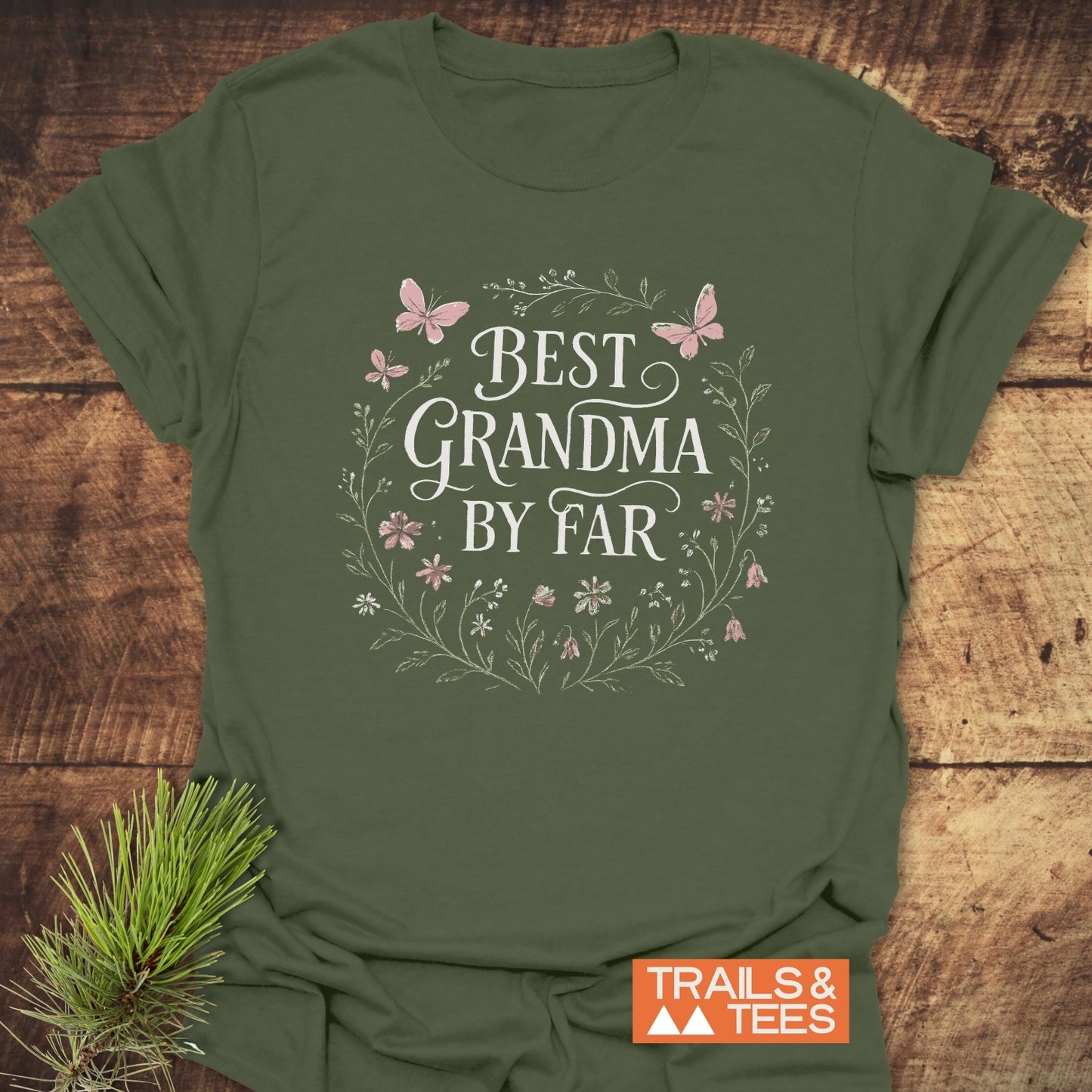 Olive-green Best Grandma Flower T-Shirt with a floral wreath design and slogan, laid flat. Features soft cotton, durable print, and taped shoulders for comfort.