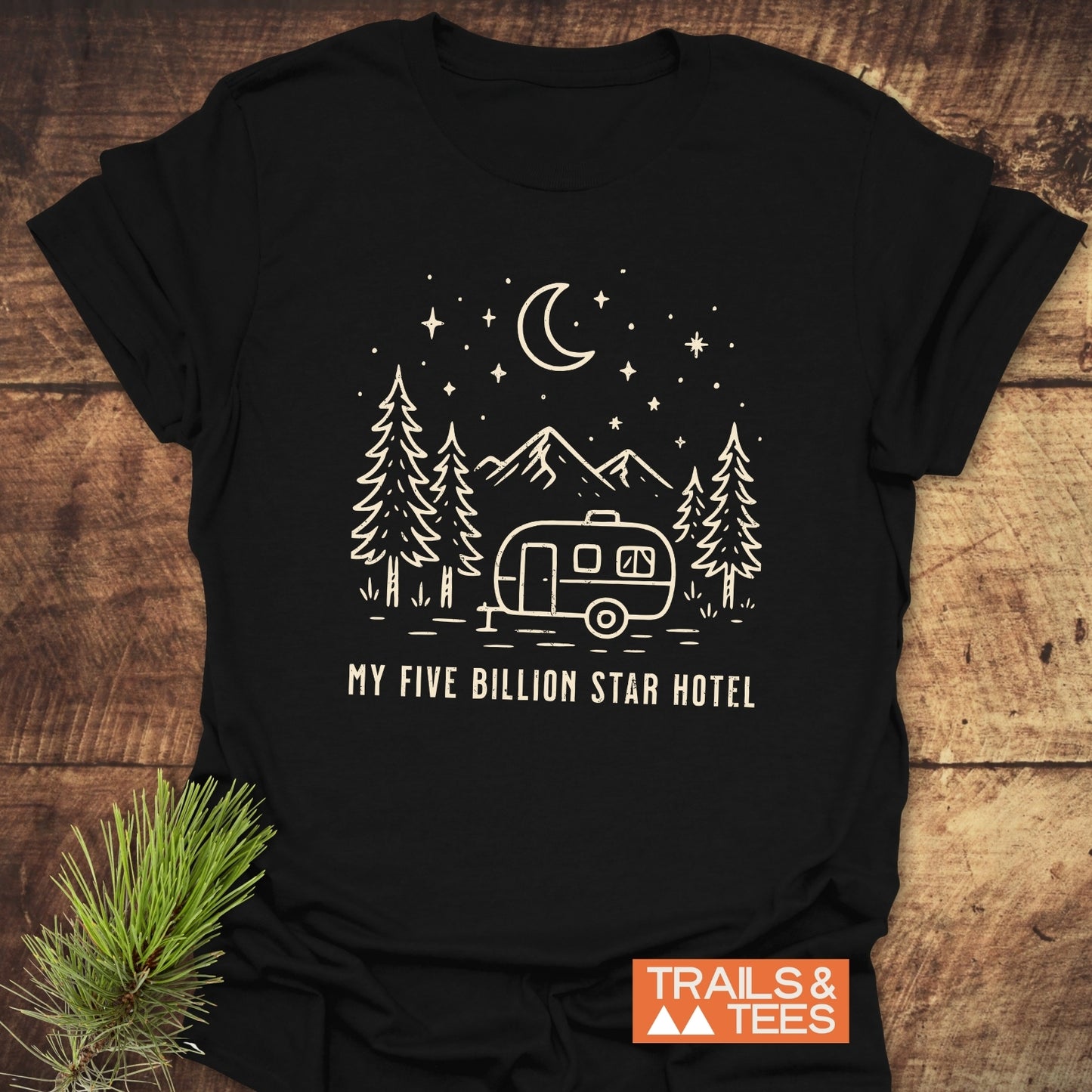 Black t-shirt with a line-drawing of a trailer, trees, mountains, and stars, featuring MY FIVE BILLION STAR HOTEL slogan; Trails & Tees logo visible.