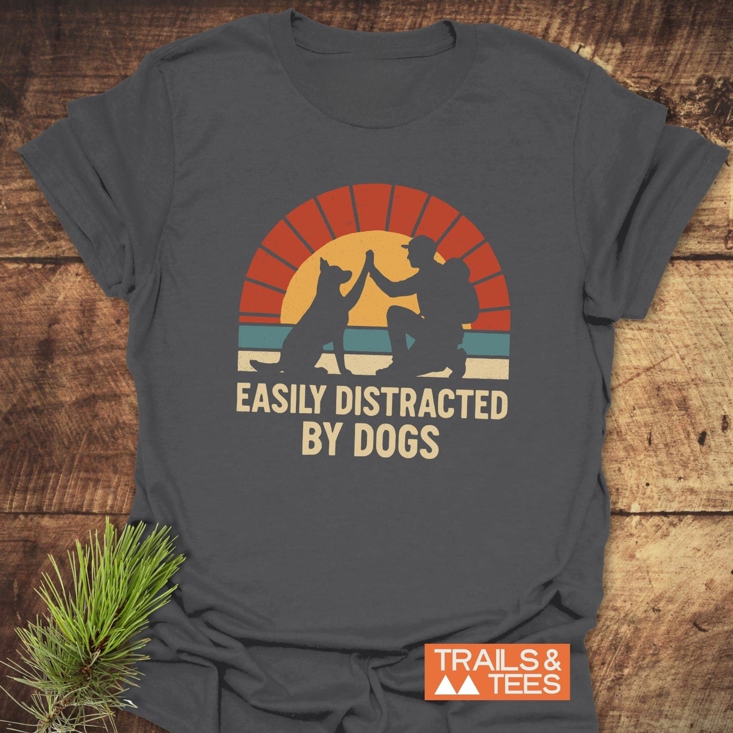 Easily Distracted By Dogs T-Shirt featuring a hiker and dog graphic with slogan, designed for comfort and adventure, pine sprig accents the scene.