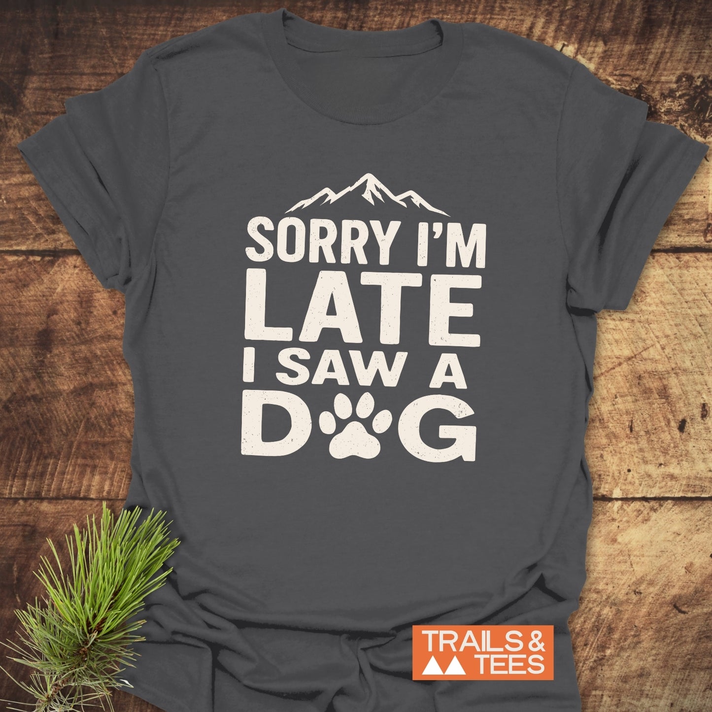 I Saw A Dog T-Shirt with mountain silhouette, off-white text, and paw print. Trail-tested comfort, soft cotton, pre-shrunk. 'TRAILS & TEES' logo included.