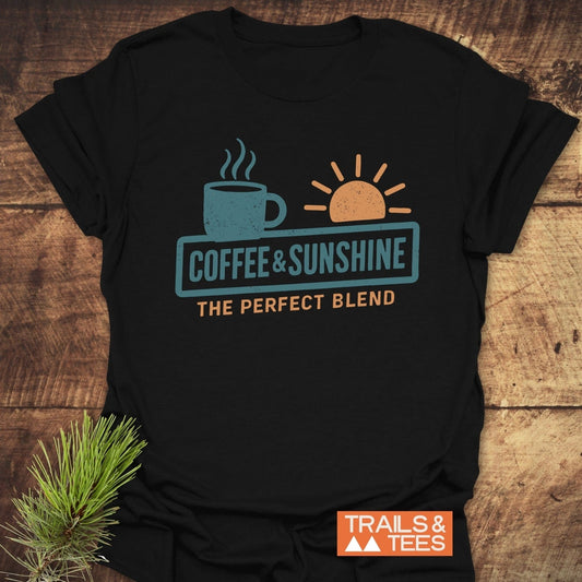 Coffee & Sunshine T-Shirt: Black tee featuring a steaming coffee mug and sun graphic, crafted from soft cotton for comfort and durability, ideal for outdoor enthusiasts.