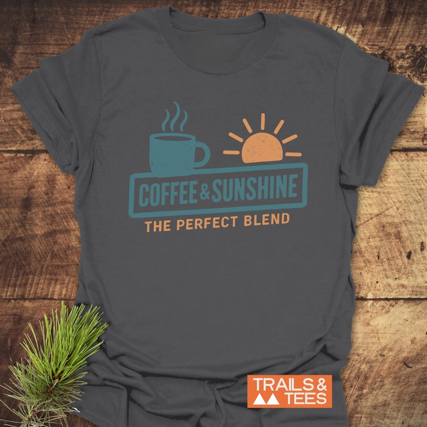 Coffee & Sunshine T-Shirt with cozy coffee mug and sun graphic, crafted from soft ring-spun cotton, featuring durable prints and a Trails & Tees logo.