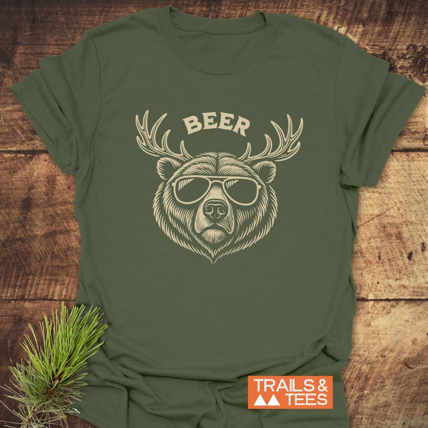 Forest-green Beer Funny T-Shirt featuring bear with antlers and sunglasses graphic. Includes TRAILS & TEES logo, crafted for comfort and durability, ideal for outdoor enthusiasts.
