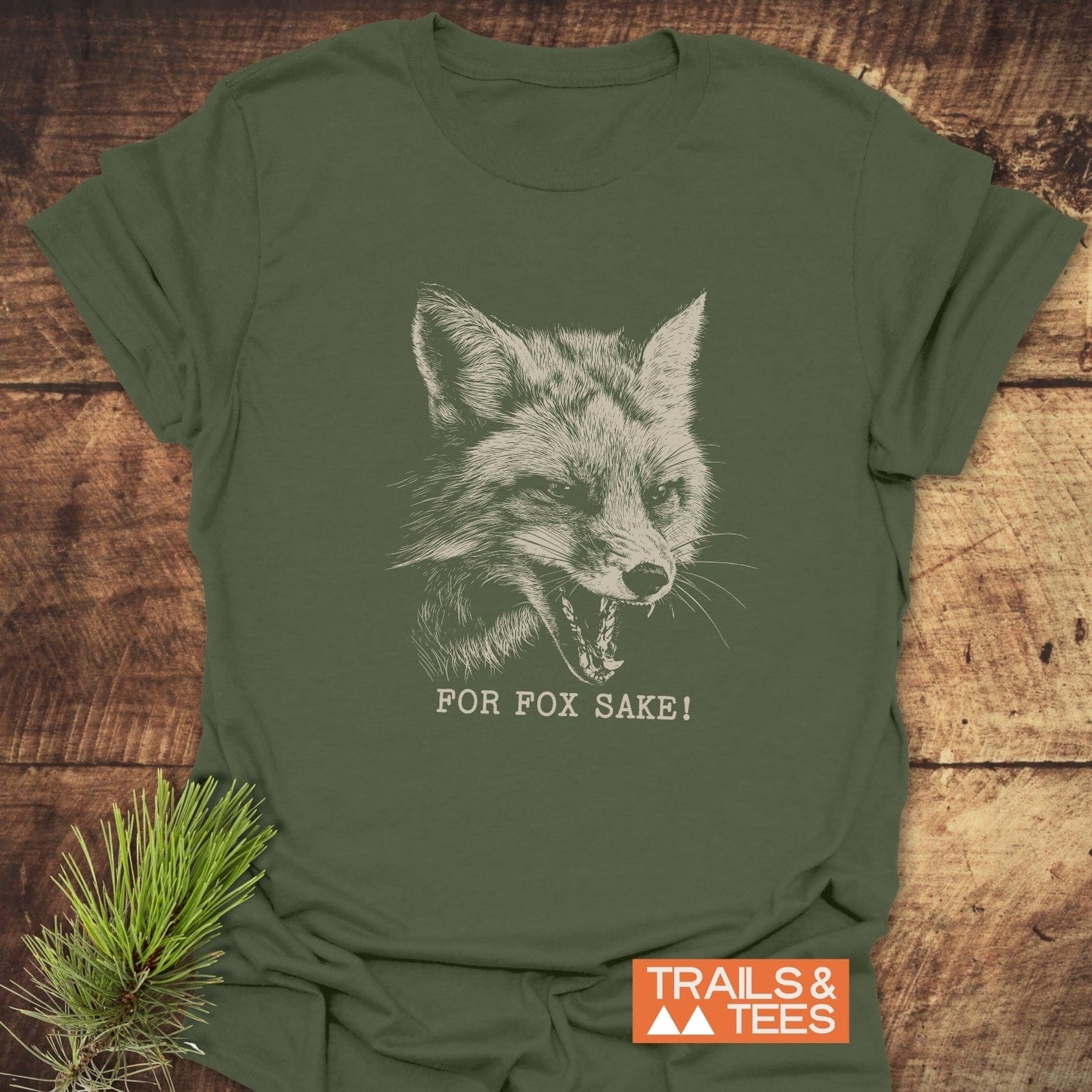 For Fox Sake! Funny T-Shirt featuring a detailed fox illustration, crafted from soft ring-spun cotton with durable prints, laid flat on wood.