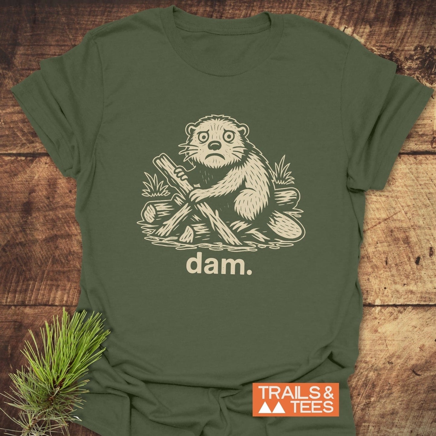 Beaver - Dam Funny T-Shirt: Olive-green tee with a cream cartoon beaver illustration and dam. text, showcasing outdoor-themed humor and comfort from TRAILS & TEES.