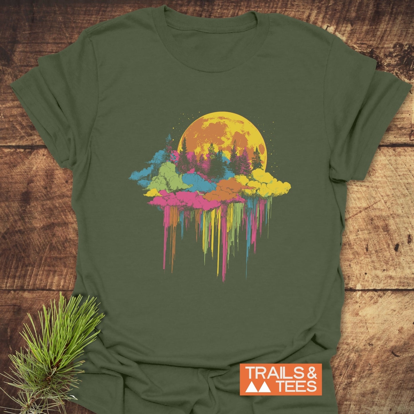 Moonlight Meltdown T-Shirt featuring a moon and pine tree graphic, laid on wood, embodies adventure-ready comfort with durable, pre-shrunk cotton and vibrant design.