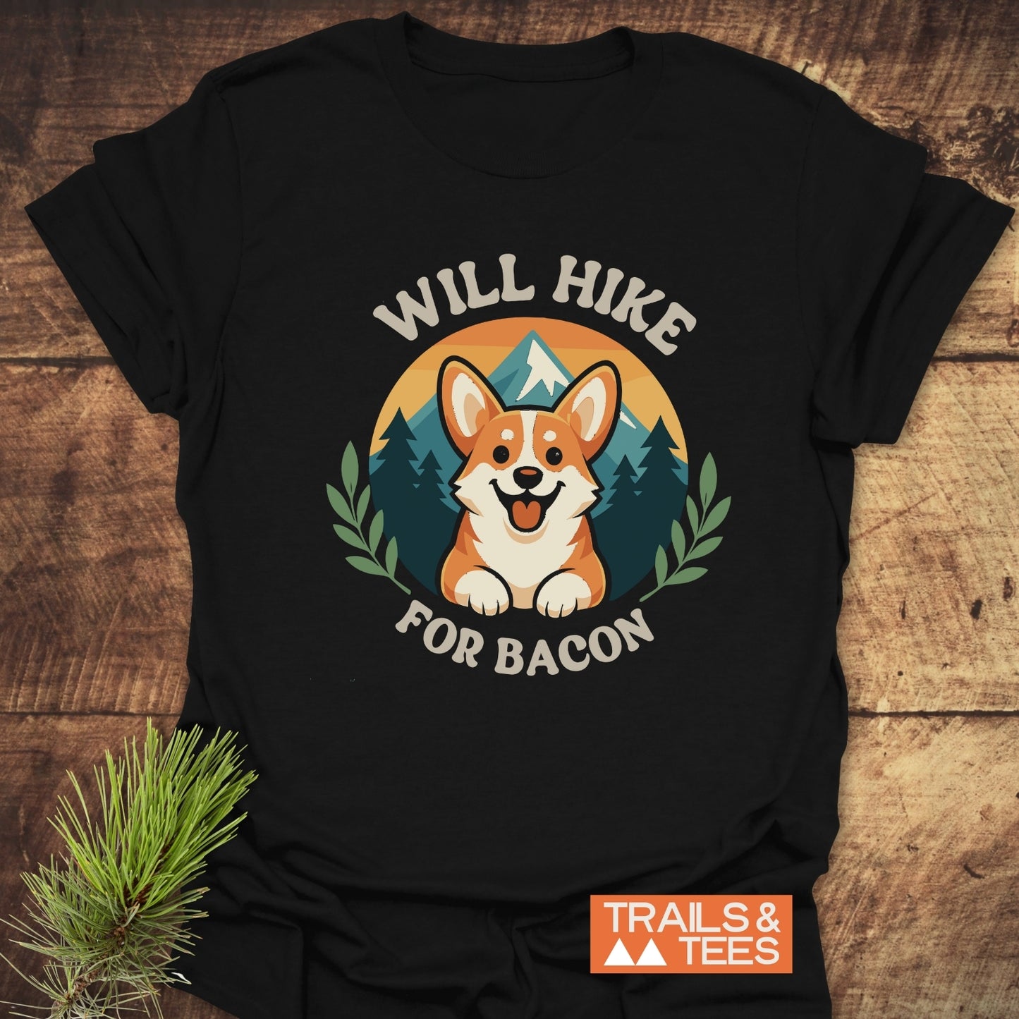 Will Hike For Bacon T-Shirt featuring a cartoon Corgi with mountains, made of soft cotton, durable print, and designed for outdoor enthusiasts.