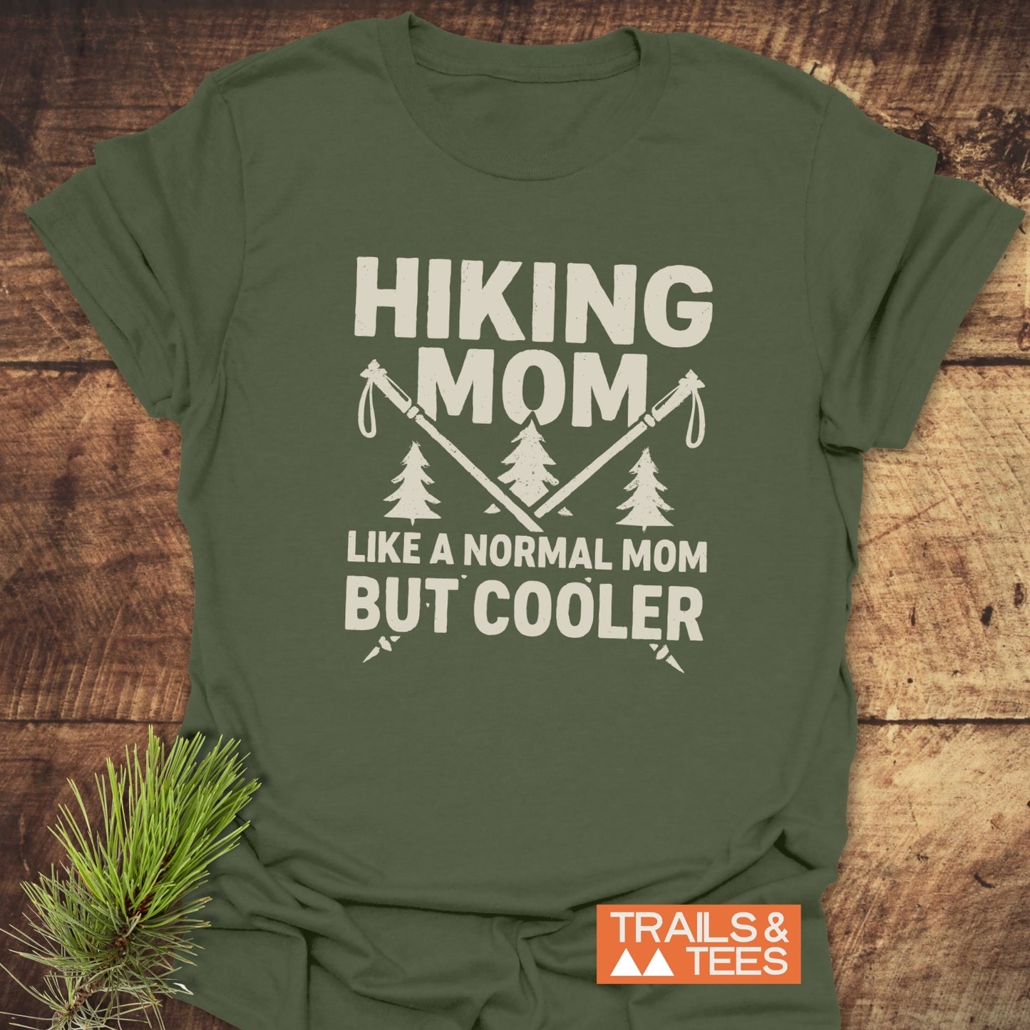 Forest-green Hiking Mom T-shirt with trekking poles and pine tree design, showcasing outdoor spirit. Crafted from soft cotton, durable, pre-shrunk for a consistent fit.