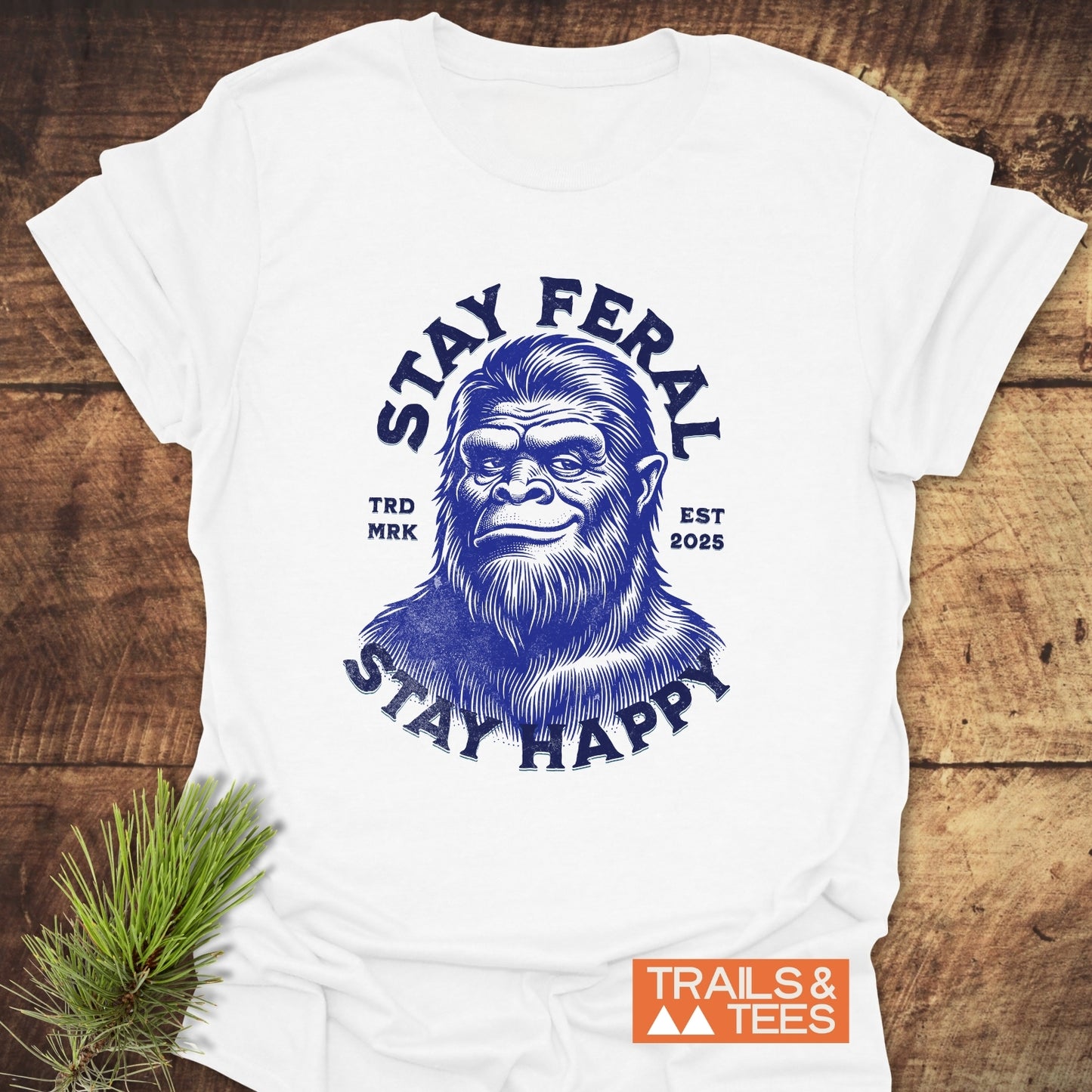 Stay Feral, Stay Happy T-Shirt featuring a blue Bigfoot illustration with arched text, crafted from soft ring-spun cotton for outdoor adventures.
