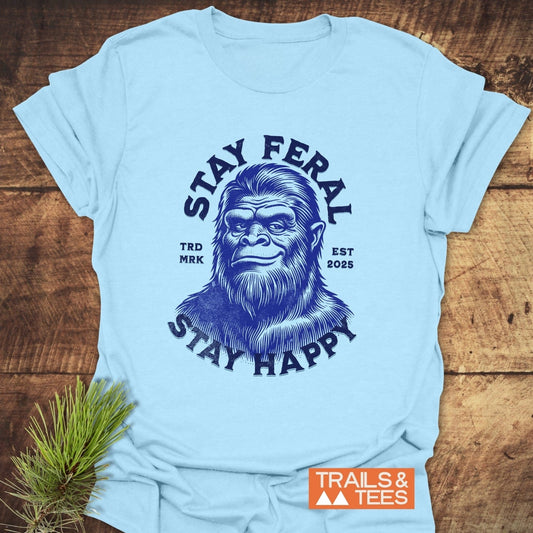 Stay Feral, Stay Happy T-Shirt featuring a bigfoot face and slogans, crafted from soft cotton for comfort and durability, styled with pine sprig accent.