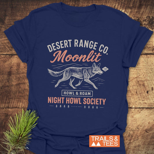 Navy-blue Night Howl Society T-shirt with coyote design and text, laid on wood. Offers comfort with durable, pre-shrunk cotton, ideal for outdoor enthusiasts.