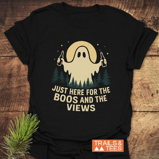 Black T-shirt with cartoon ghost and forest graphic, slogan Just Here For The Boos And The Views. Trails & Tees logo in corner.