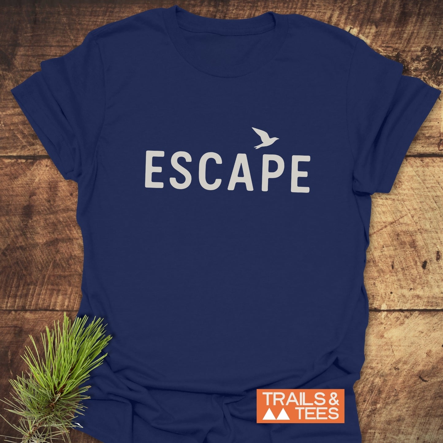 Escape Minimal T-Shirt with ESCAPE and bird print on navy, laid on wood; soft, ring-spun cotton, pre-shrunk, durable, for outdoor enthusiasts.