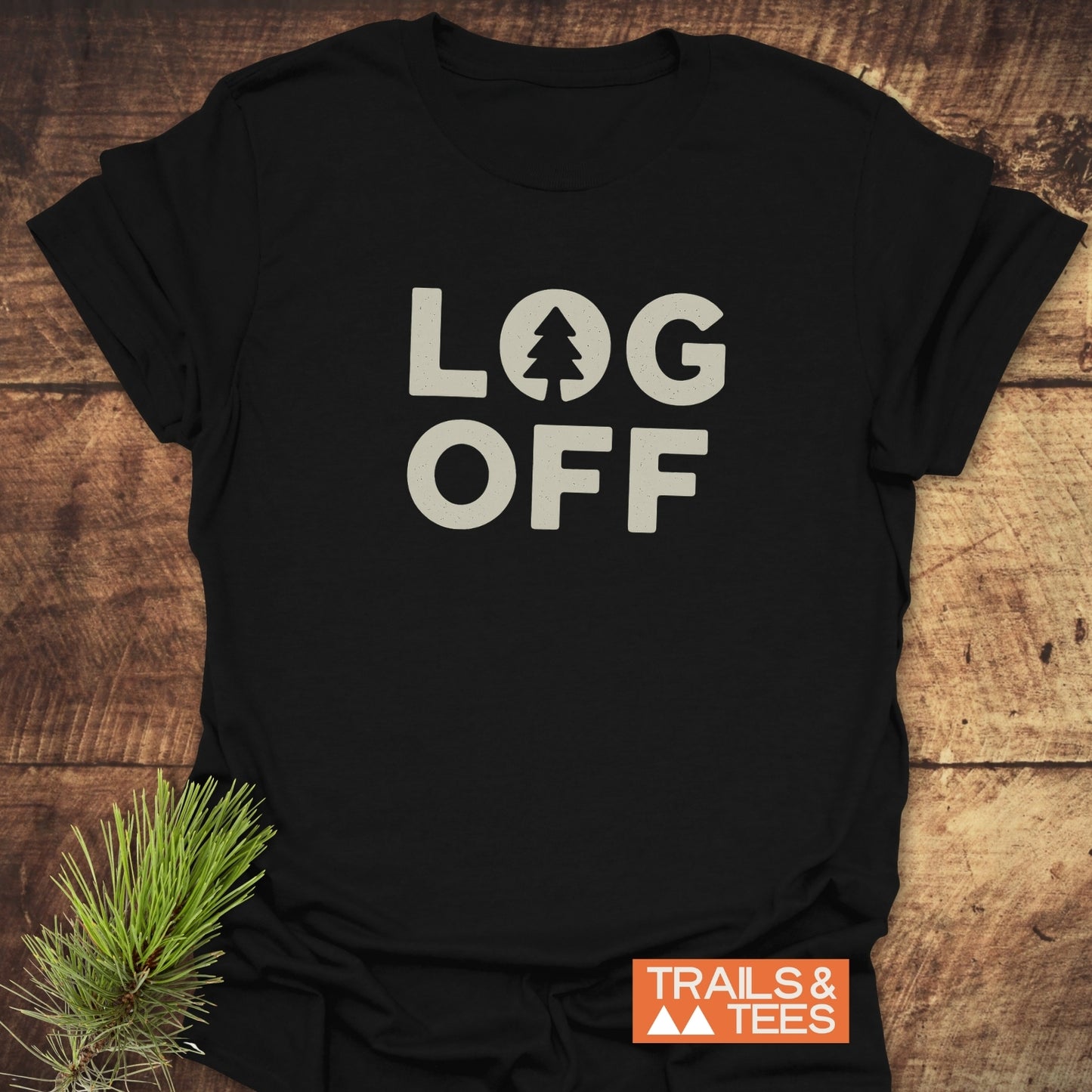 Log Off T-Shirt with LOG OFF design and pine tree graphic on black fabric, styled with pine needles; features soft, durable, adventure-ready cotton.