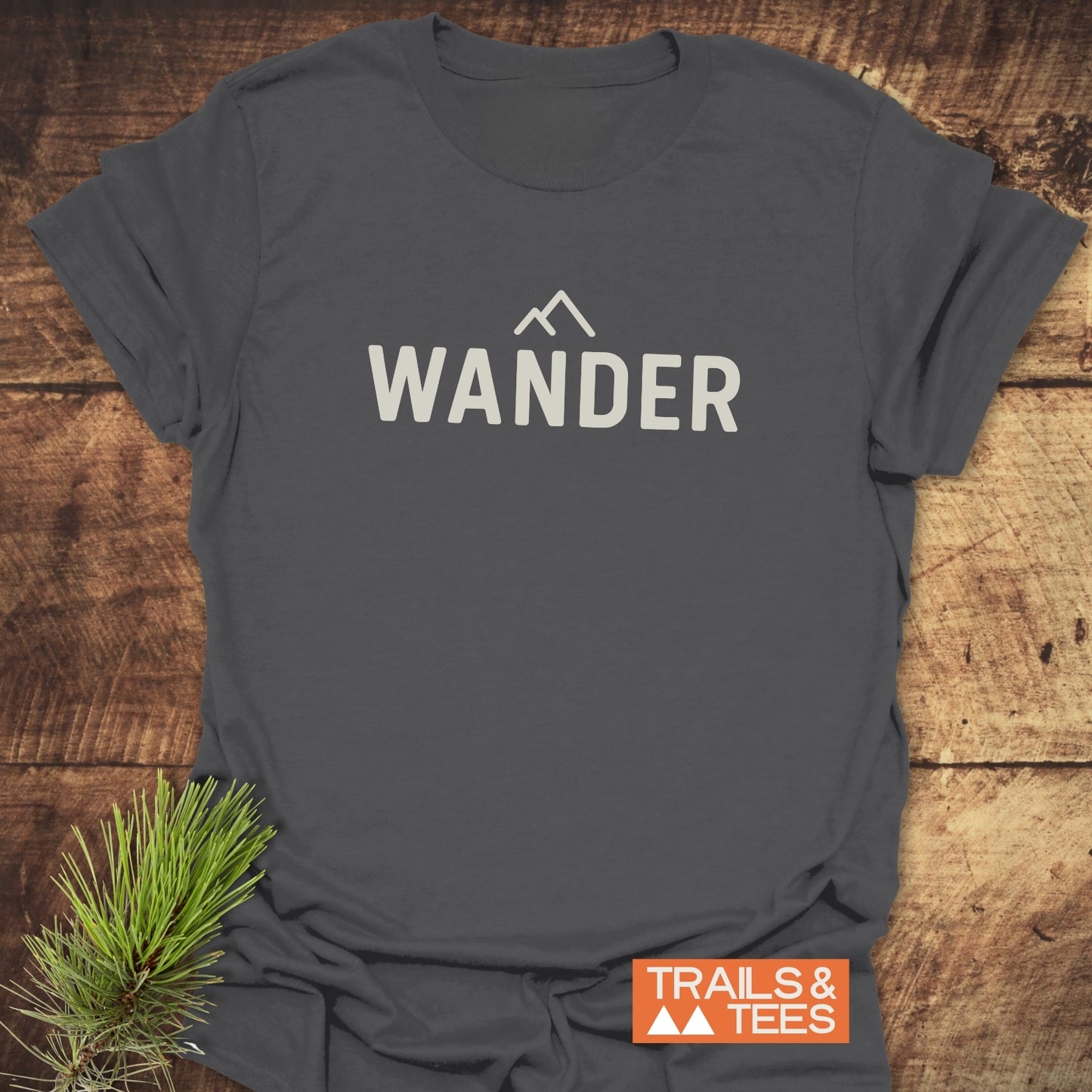 Heather-gray 547 Wander Minimalist T-Shirt with bold WANDER text and mountain icon. Includes TRAILS & TEES badge; designed for everyday outdoor adventures.