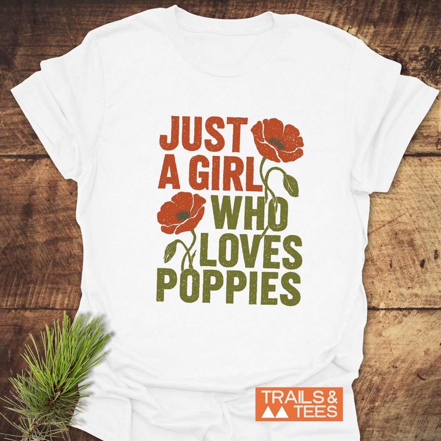 Grunge Poppy Love T-Shirt on wooden surface, featuring vintage-style text and poppy illustrations. Includes Trails & Tees logo, emphasizing outdoor-inspired, durable, and comfortable design.