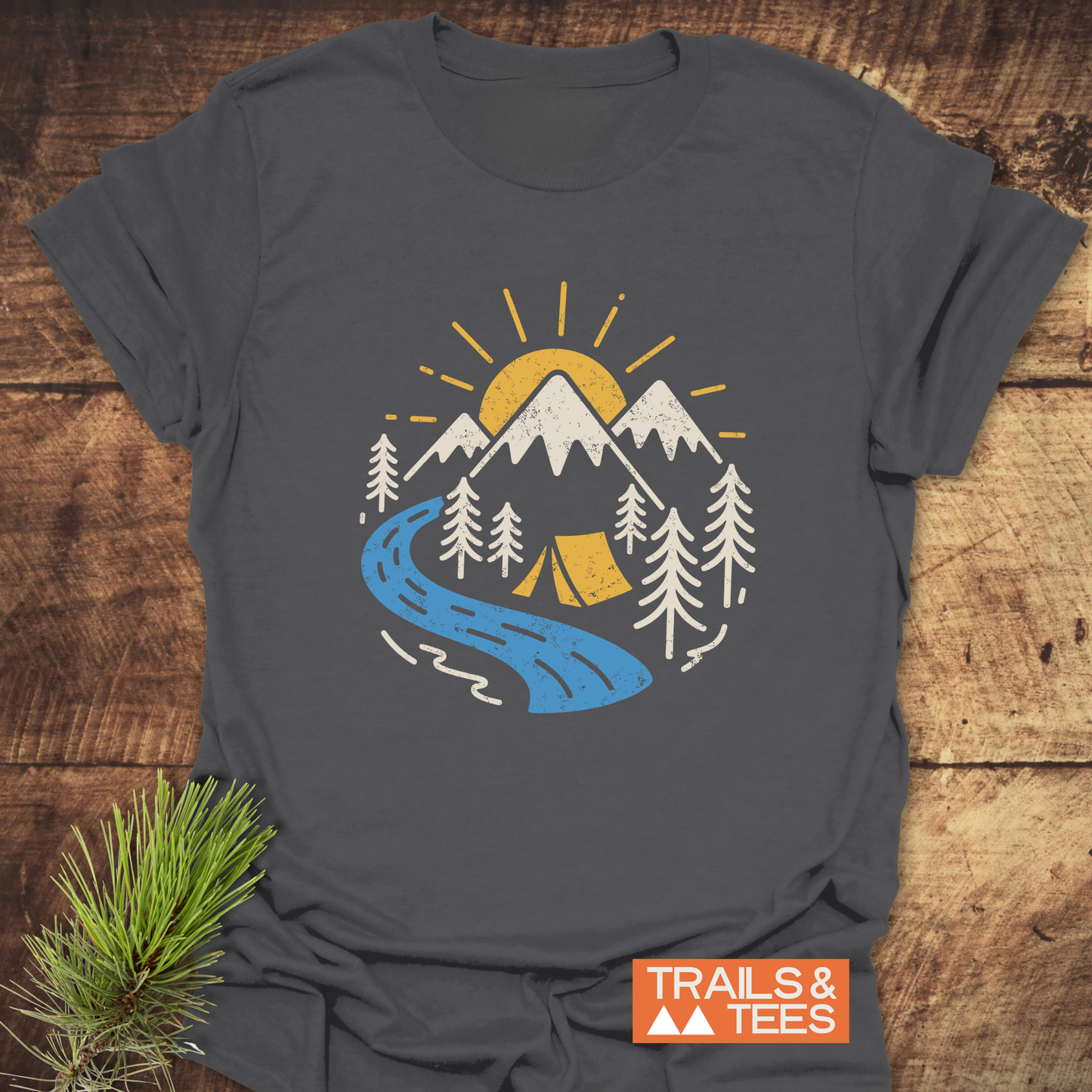 Camping Love T-Shirt featuring a distressed outdoor scene with mountains, river, trees, and tent, on soft, lightweight cotton for adventures. Orange TRAILS & TEES. label.