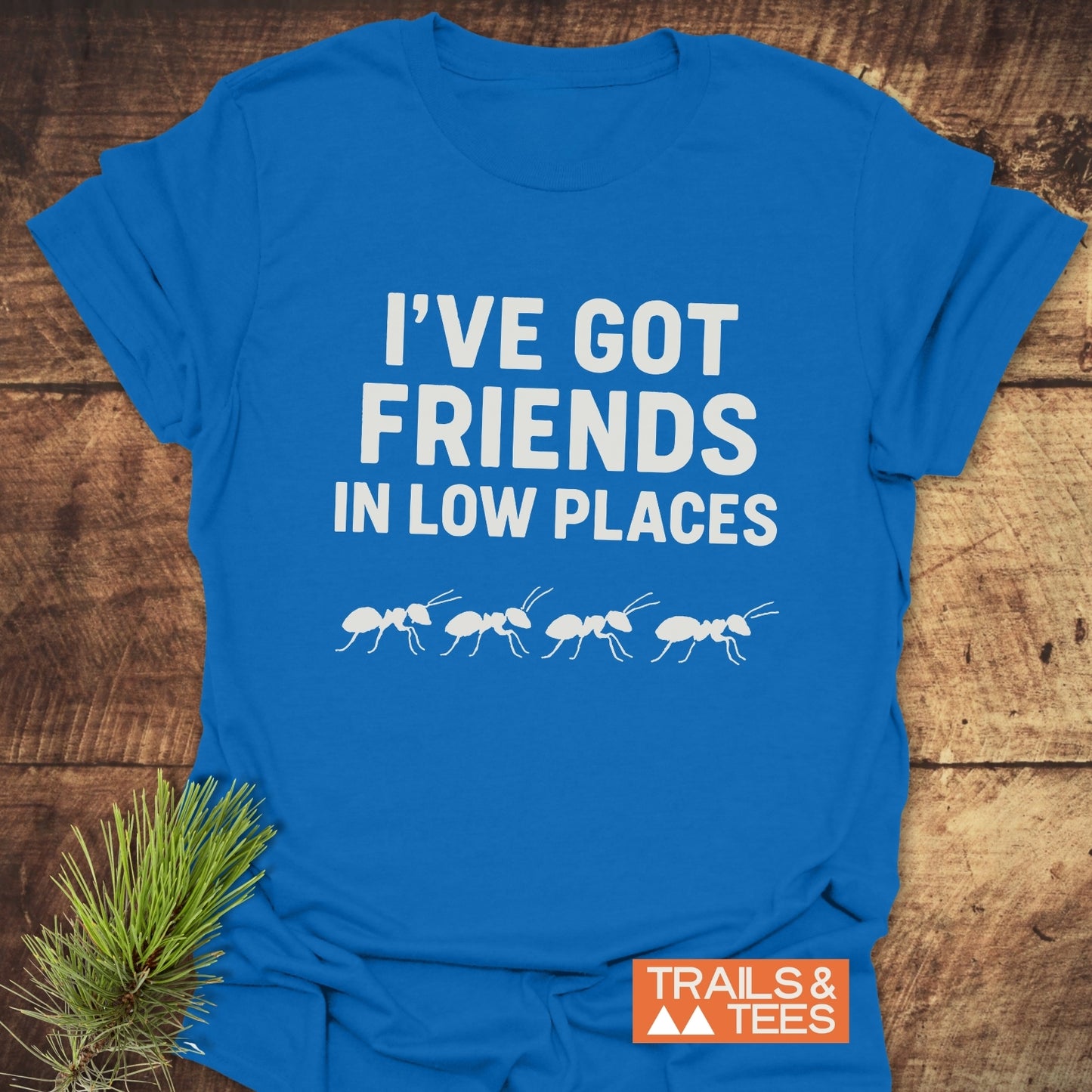 Friends In Low Places Funny T-Shirt featuring bold white text and ant silhouettes, crafted from soft cotton with durable prints, showcasing outdoor-inspired design.