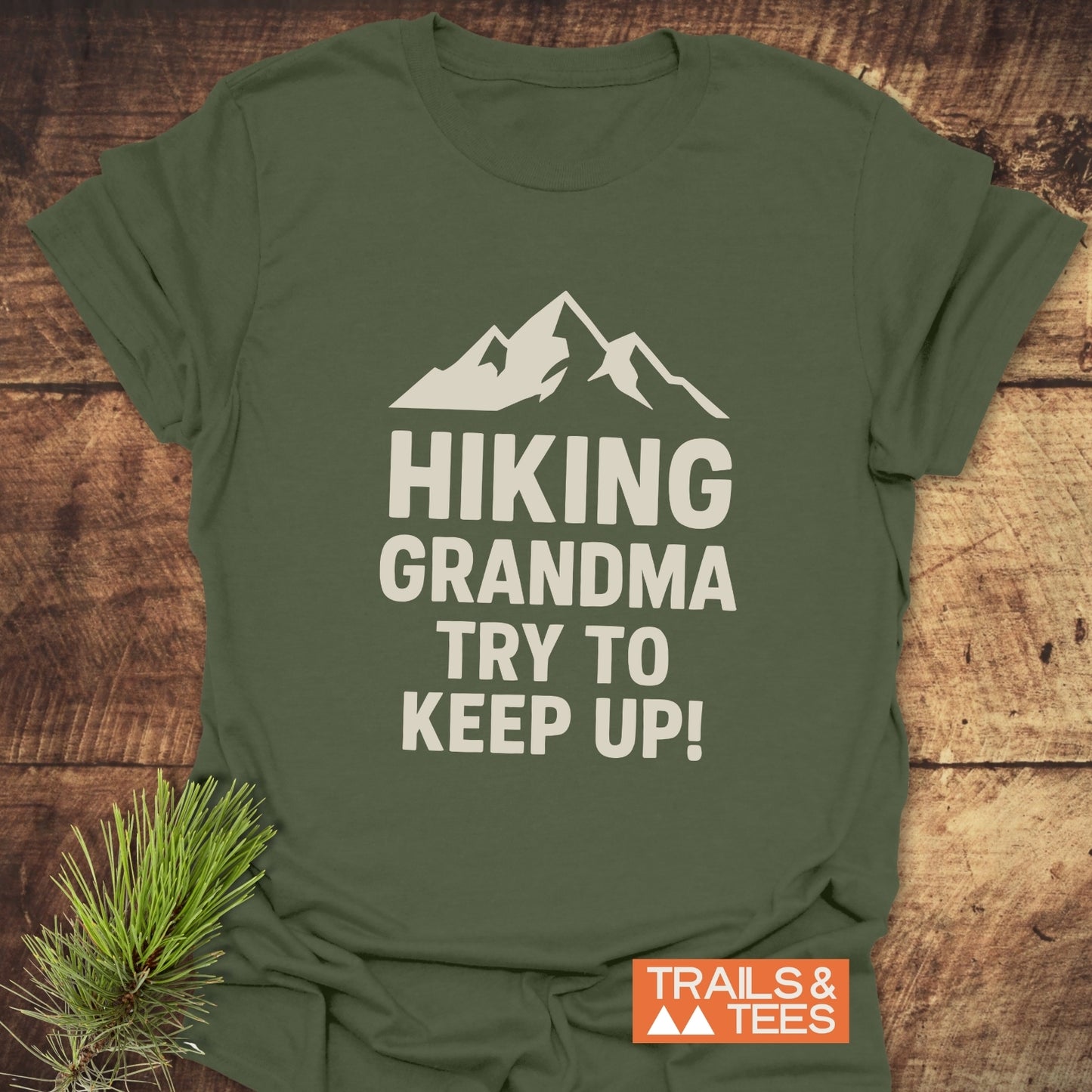 Dark-green Hiking Grandma - Try To Keep Up T-shirt, featuring a mountain graphic. Displayed flat with a TRAILS & TEES logo, emphasizing comfort and durability.
