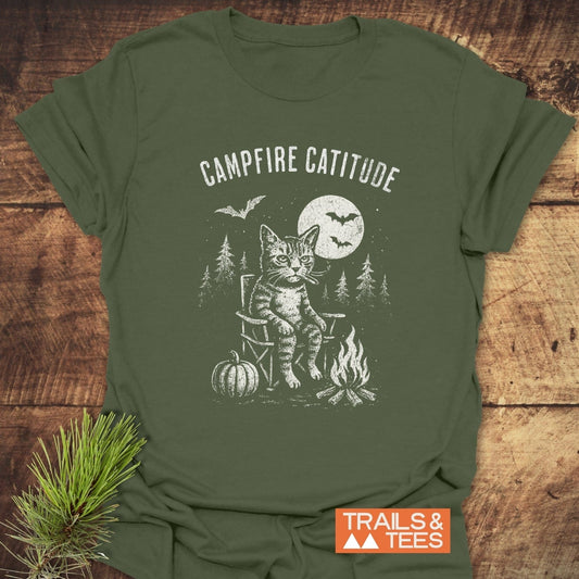 Campfire Catitude T-Shirt featuring a grumpy cat, campfire, and pine trees, crafted from soft cotton, offering durable prints and a pre-shrunk fit.